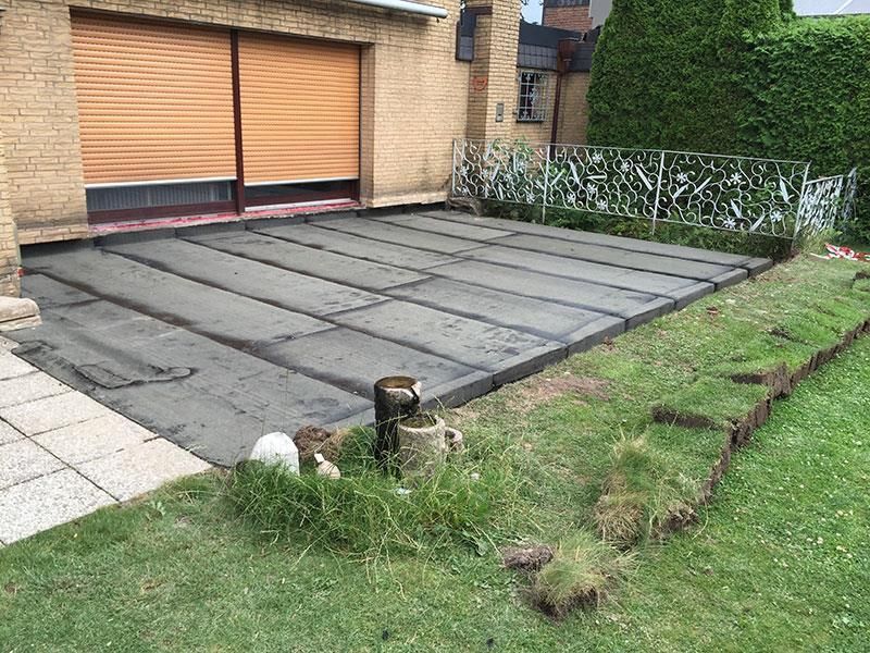 Ein Backsteinhaus mit einem Garagentor und einer Betonauffahrt davor.