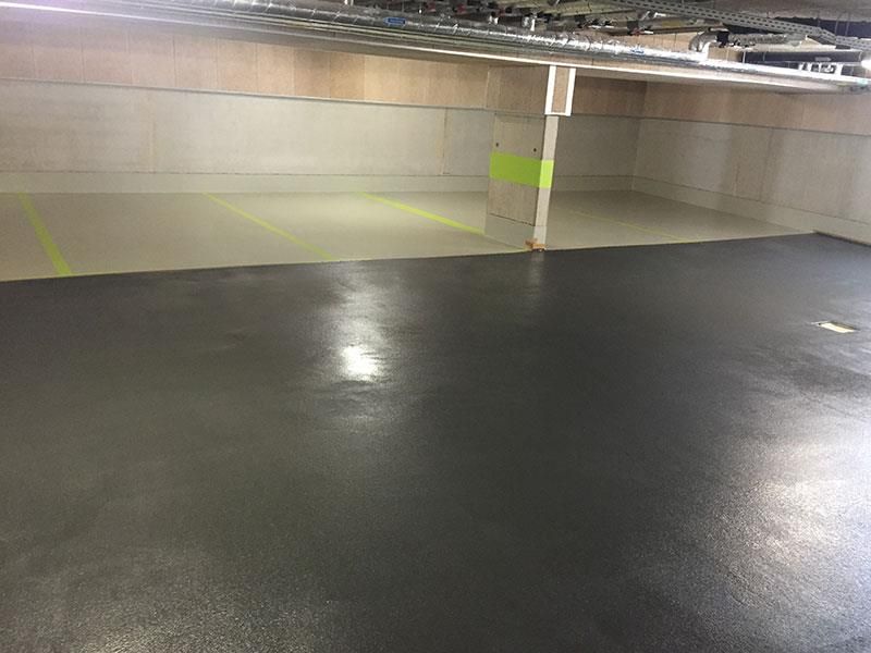 Ein Parkhaus mit schwarzem Boden und einer gelben Linie an der Wand.