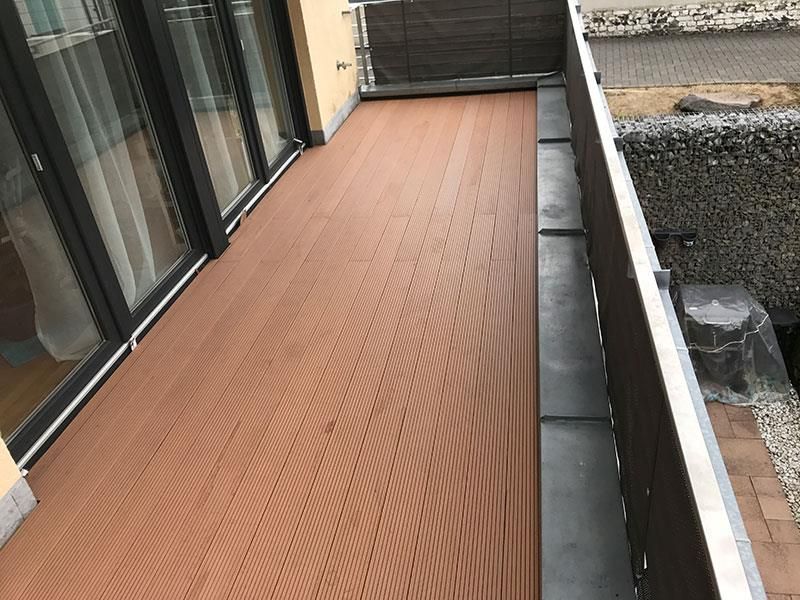 Ein Balkon mit Holzterrasse und Glasschiebetüren.