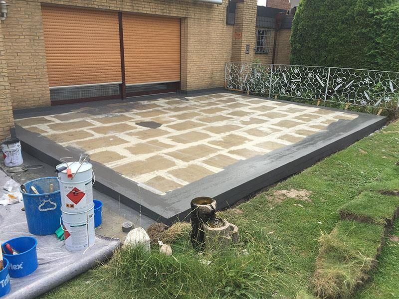 Vor einem Garagentor wird eine Terrasse gestrichen.