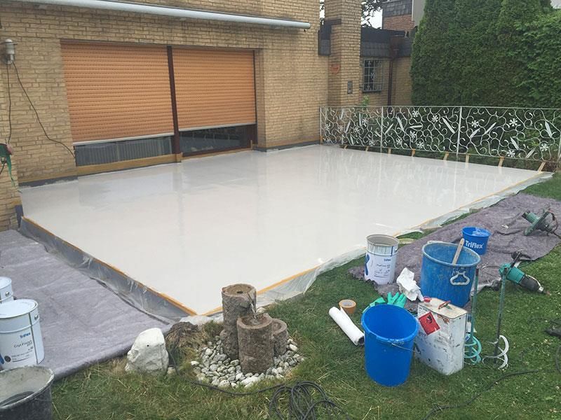 Im Hinterhof eines Hauses wird eine Terrasse gestrichen.