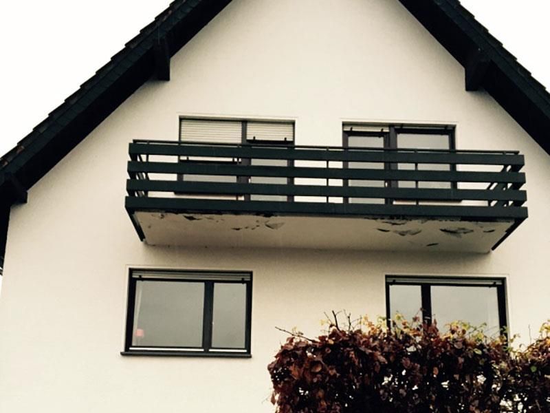 Ein weißes Haus mit einem schwarzen Balkon und Fenstern