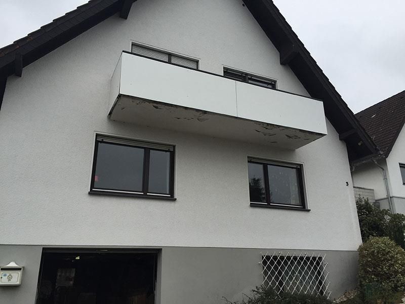 Ein weißes Haus mit Balkon und schwarzen Fenstern