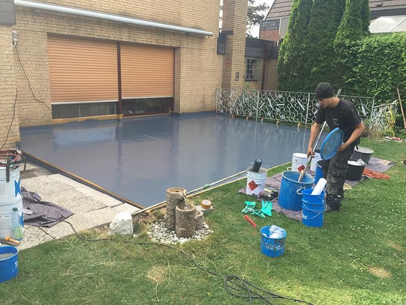 Ein Mann gießt in einem Hinterhof Farbe in Eimer.