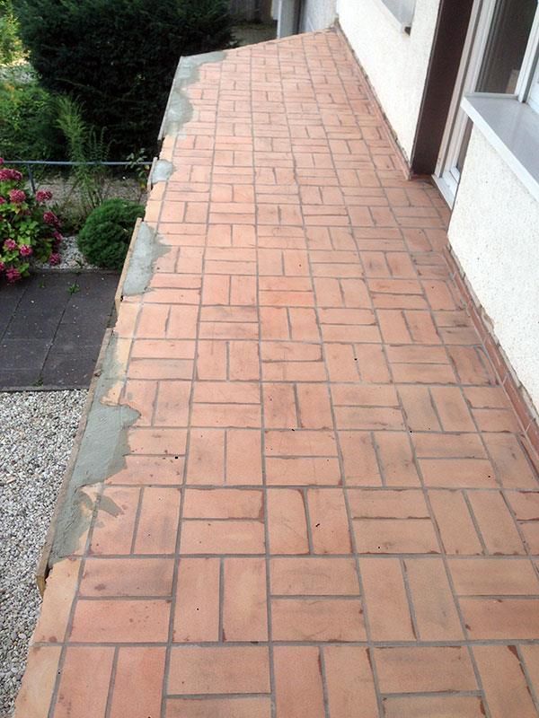 Ein gemauerter Gehweg, der zu einem weißen Gebäude führt