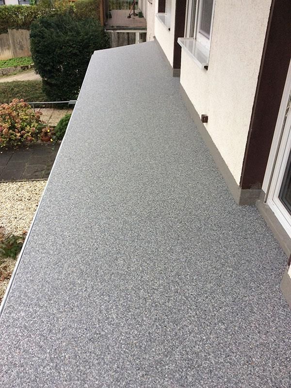 Ein Balkon mit grauem Betonboden und einem Fenster.