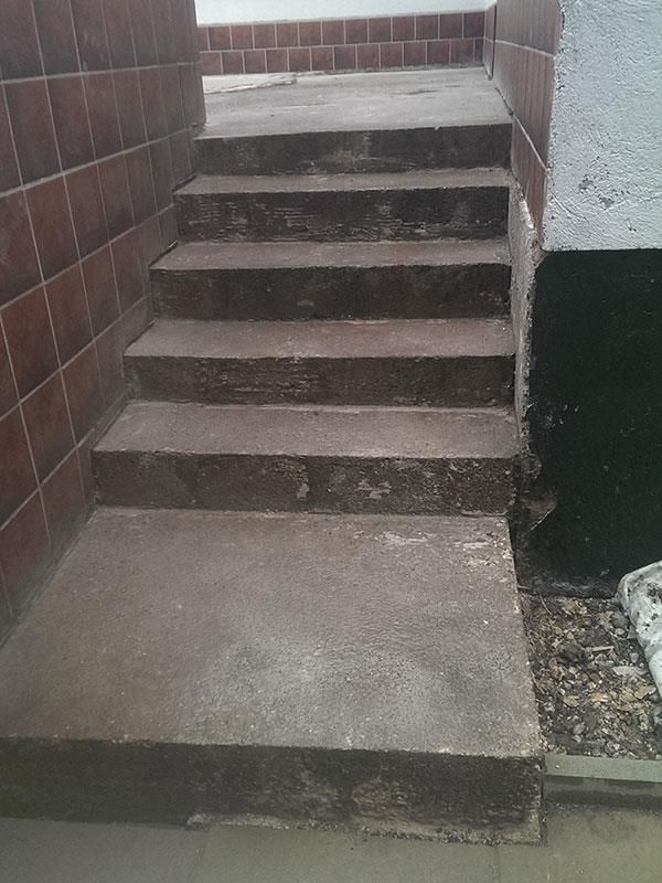 Eine Treppe, die zu einer Backsteinmauer hinaufführt.