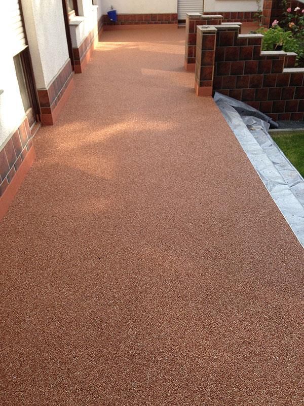 Ein Gehweg mit einer Backsteinmauer an der Seite eines Hauses.