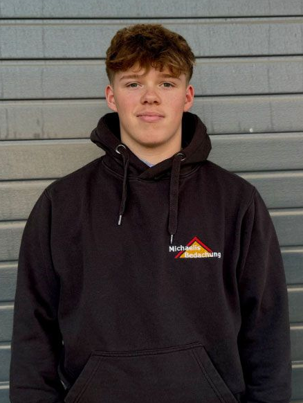 Ein junger Mann in einem schwarzen Shirt lächelt in die Kamera.