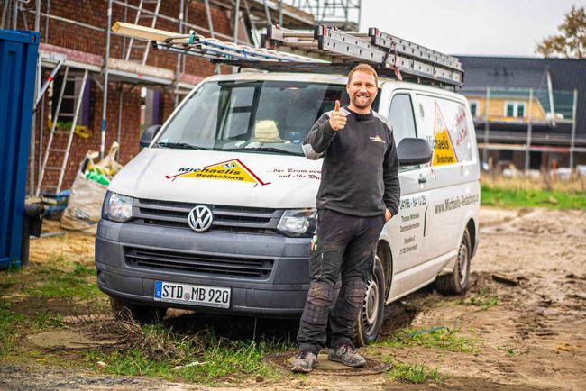Ein Mann steht vor einem Lieferwagen und zeigt seinen Daumen nach oben.