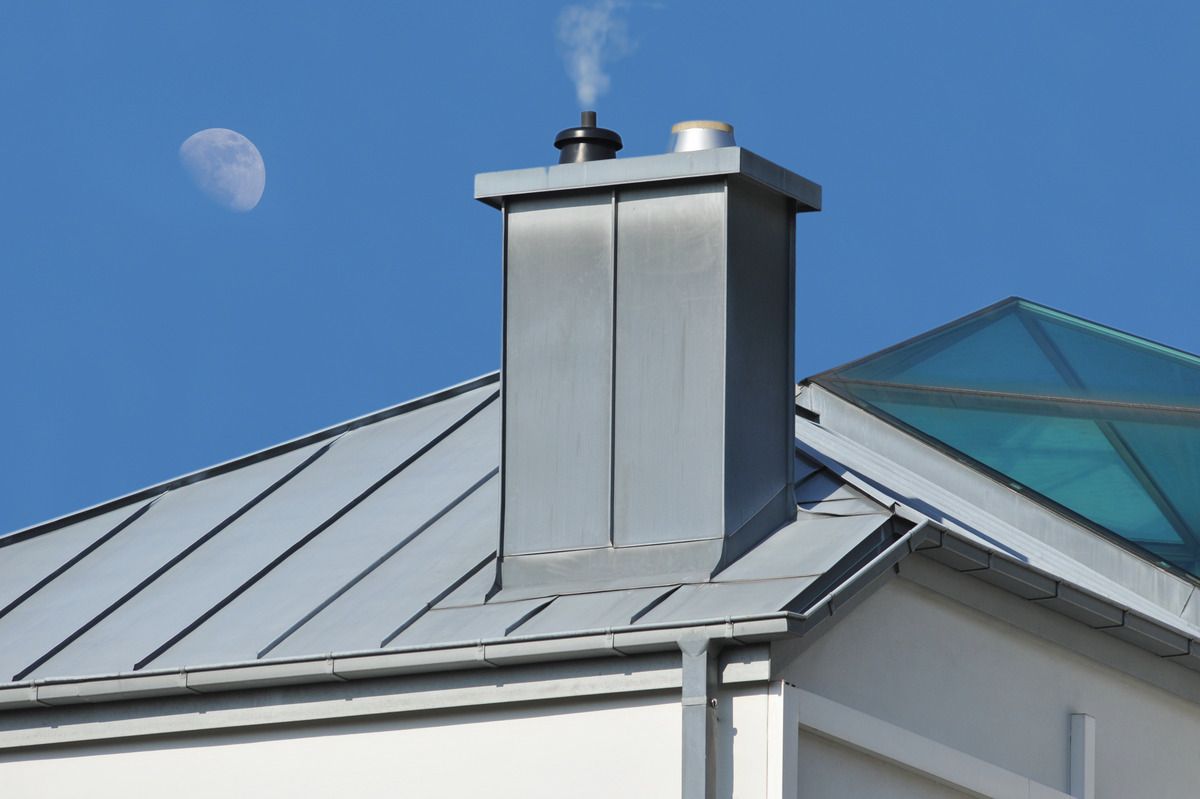 Ein Schornstein auf dem Dach eines Hauses mit dem Mond im Hintergrund