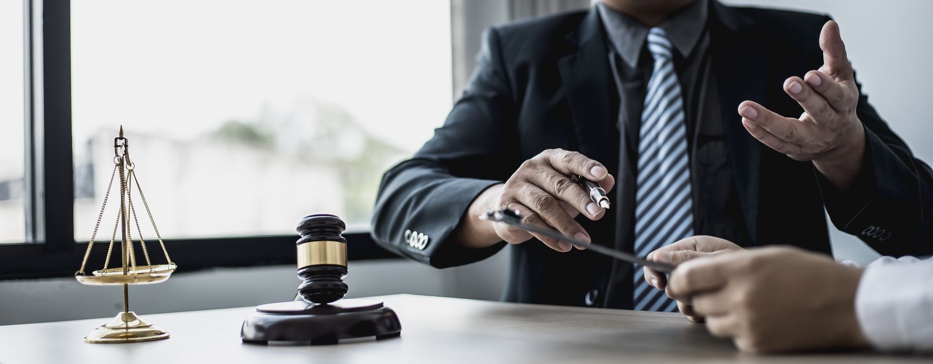 Homme à cravate rayée, assis derrière une table avec un stylo plume dans la main