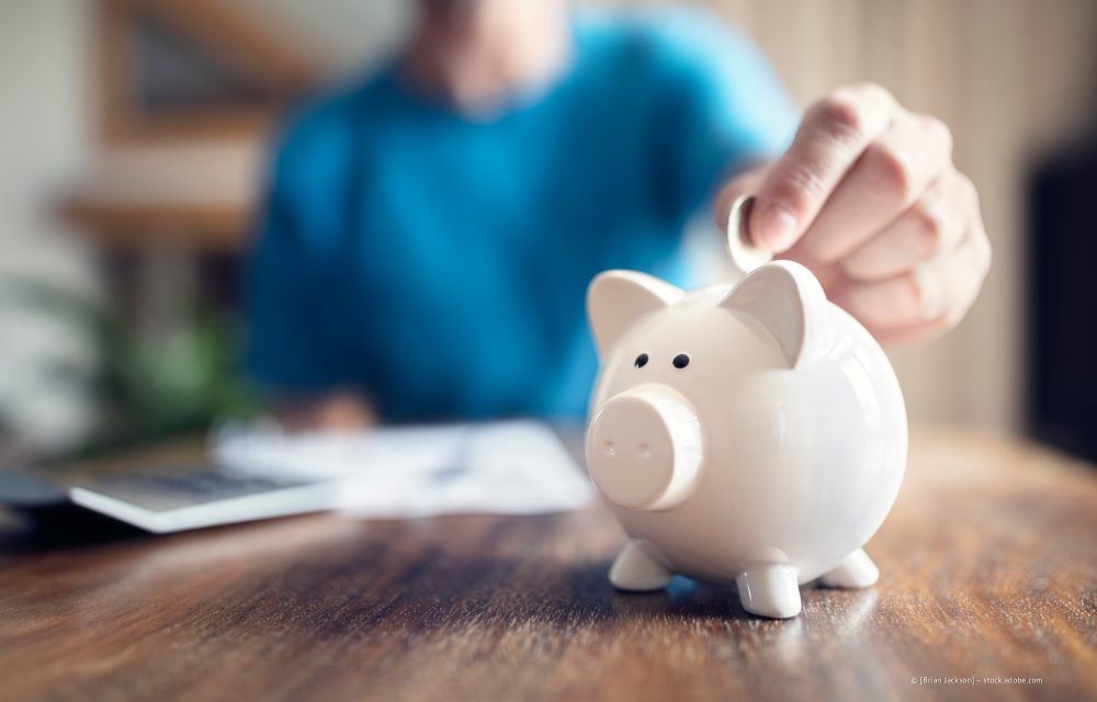 Wohnzimmer mit olivgrünem Sofa, Holztischen, Topfpflanze und Stehlampe.