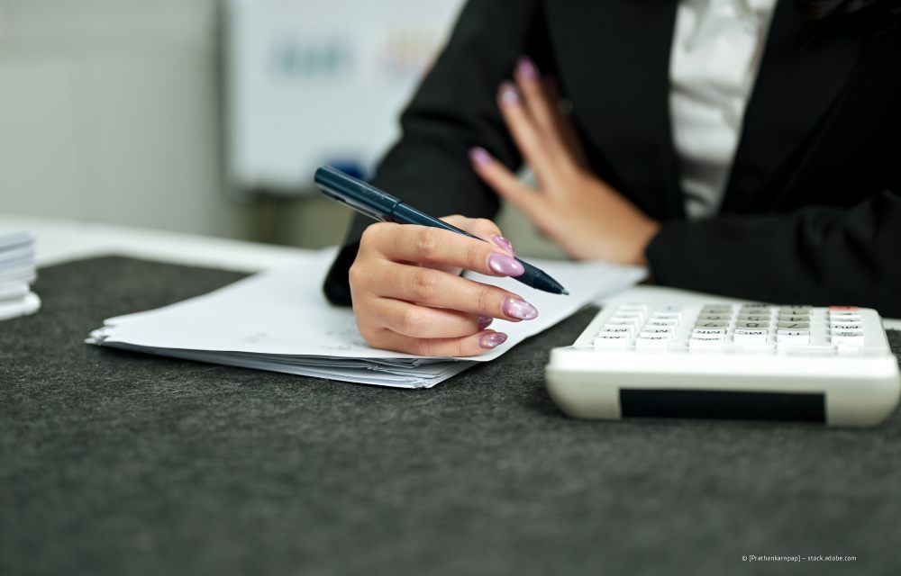 Wohnzimmer mit olivgrünem Sofa, Holztischen, Topfpflanze und Stehlampe.