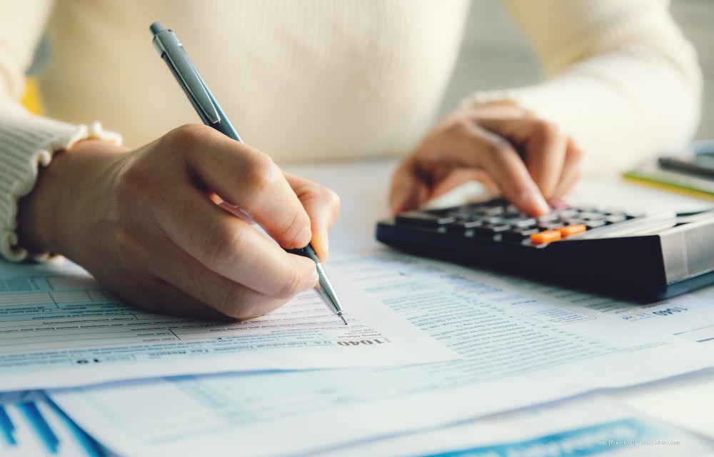 Wohnzimmer mit olivgrünem Sofa, Holztischen, Topfpflanze und Stehlampe.