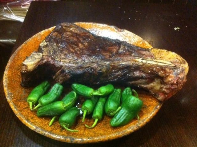 Bistec a la parrilla con pimientos verdes en un plato marrón.