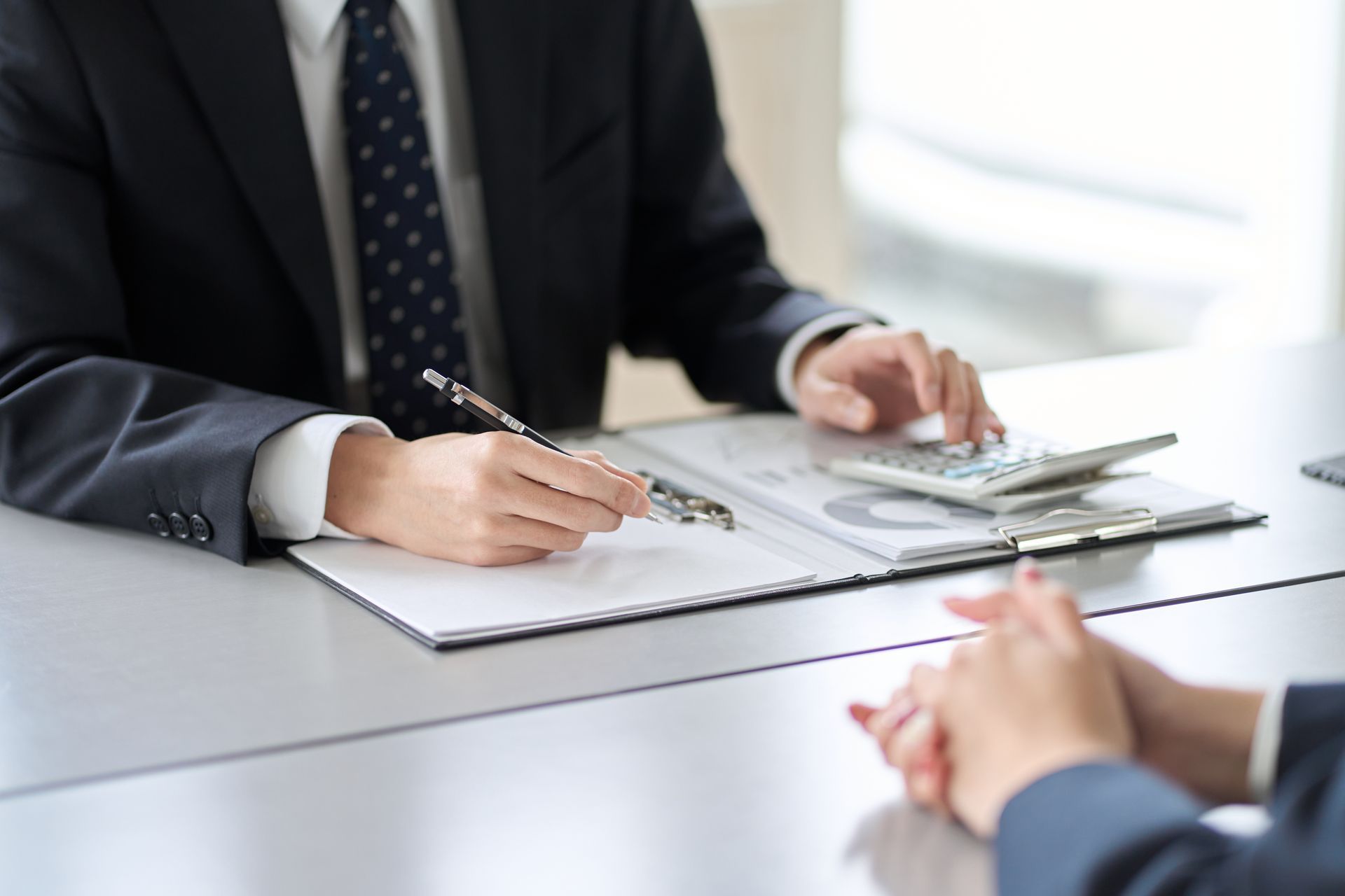 Person, die einen Taschenrechner verwendet, Papiere hält und Finanzdaten überprüft.