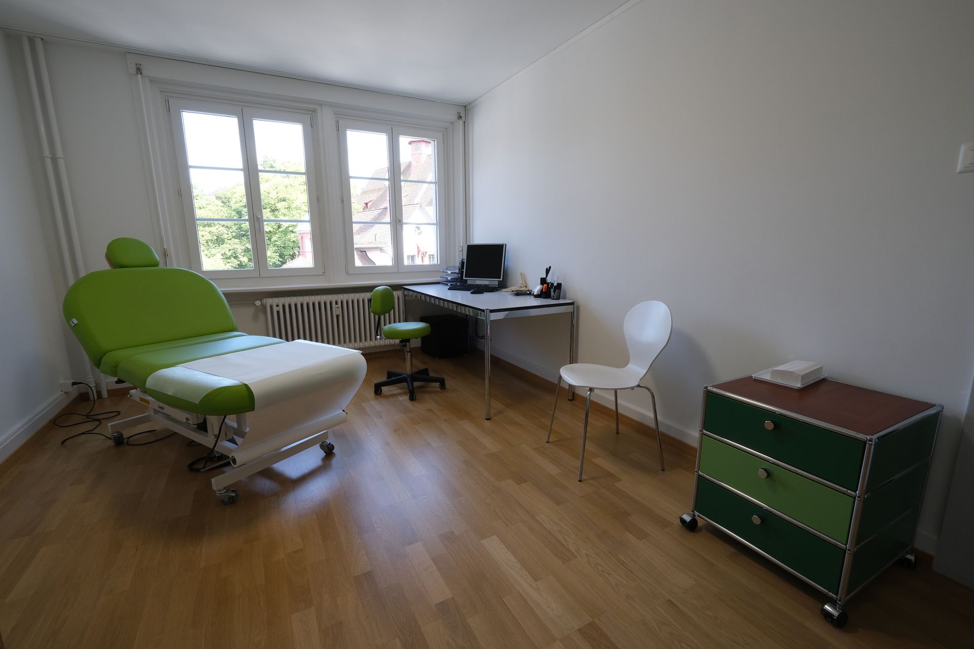 Ein Zimmer mit einem grünen Stuhl, einem Schreibtisch, einem Sessel und einer Kommode.