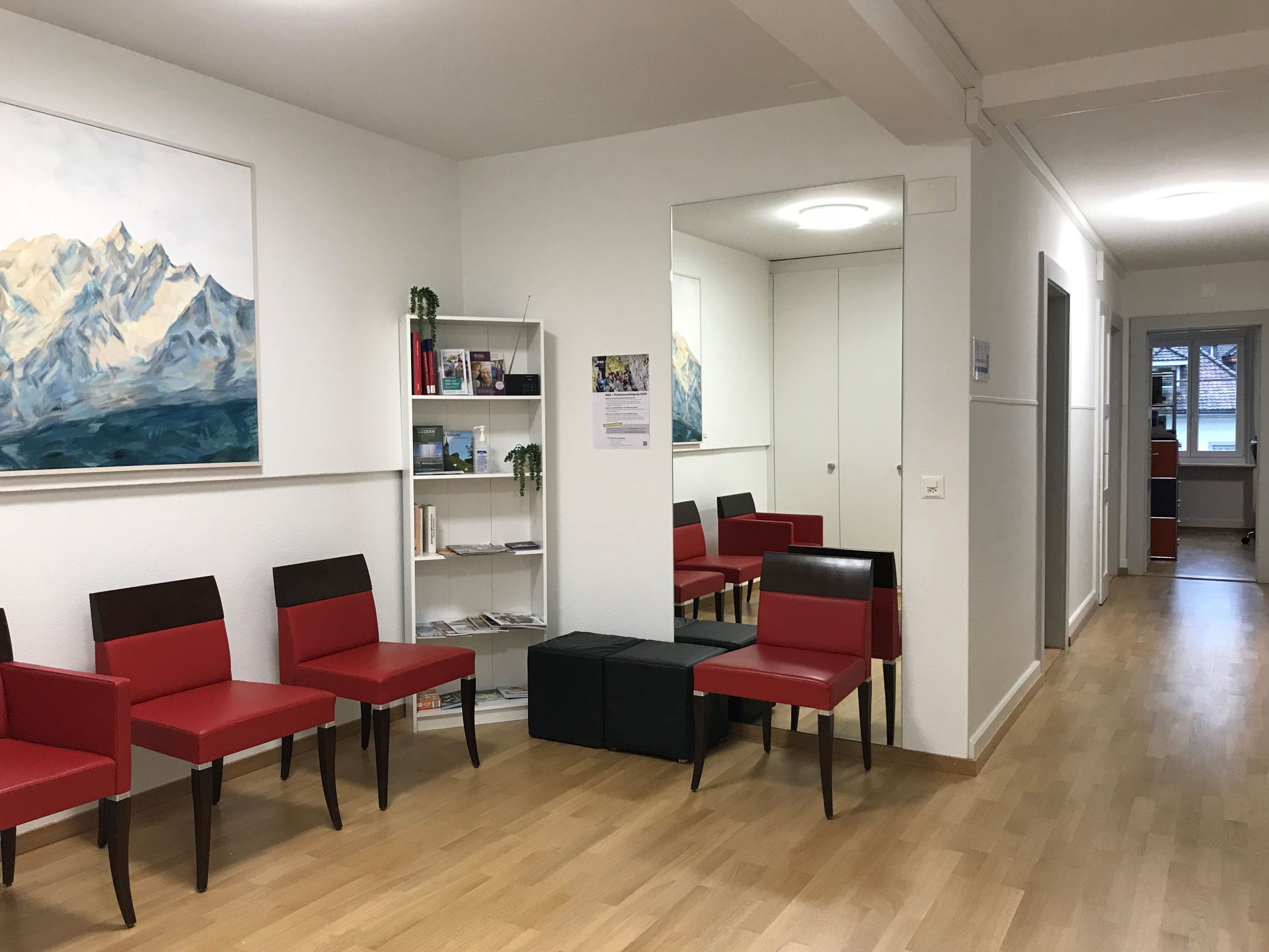 Ein Wartezimmer mit roten Stühlen und einem Gemälde an der Wand