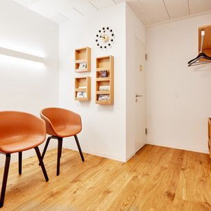 Ein Wartezimmer mit zwei Stühlen und einer Uhr an der Wand.