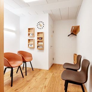 Ein Wartezimmer mit zwei Stühlen und einer Uhr an der Wand.