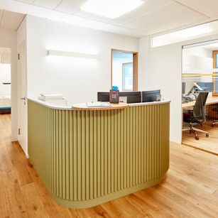 Ein grüner Empfangstresen in einem Büro mit Holzboden.