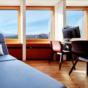 Ein Wohnzimmer mit Couch, Schreibtisch, Sessel und Computer.