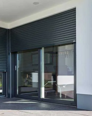 Baie vitrée avec un volet roulant noir baissé à la moitié de la fenêtre.