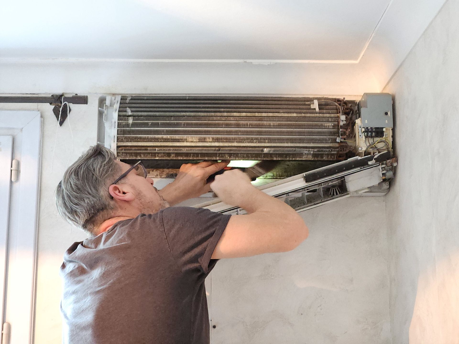 Artisan rénovant une pompe à chaleur détériorée