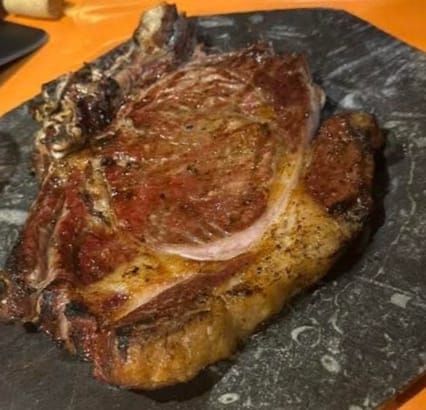 Gambas en un plato de cerámica marrón con ajo y aceite sobre una mesa de madera.