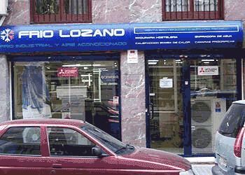 Un coche rojo está estacionado frente a una tienda llamada Frío Lozano.