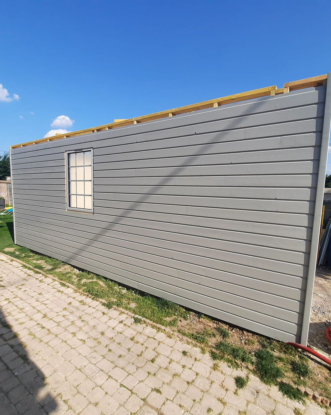 Mur d'un bâtiment aux parois grises, avec une petite fenêtre.