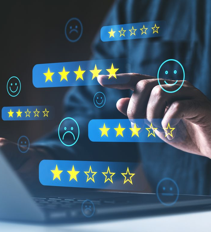 Personne utilisant un ordinateur portable, interagissant avec des icônes d'évaluation par étoiles flottantes et des émoticônes ; représentant les commentaires des clients.