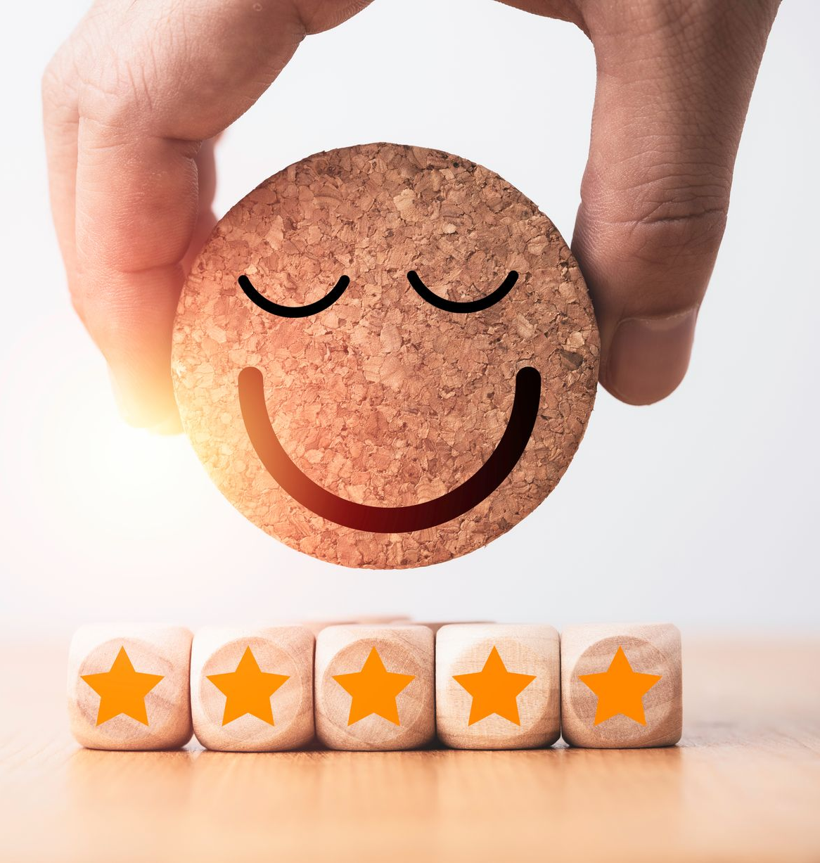 Main tenant un sous-verre en liège souriant au-dessus de blocs de notation à cinq étoiles.
