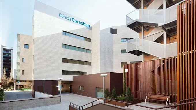 Exterior del edificio de la Clínica Corachan, arquitectura moderna, fachada de ladrillo claro, detalles en marrón, cielo azul