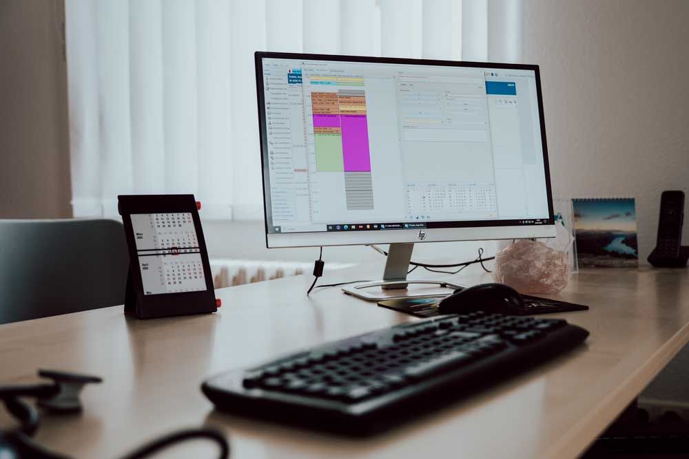 Auf einem Schreibtisch steht ein Computer neben einer Tastatur.