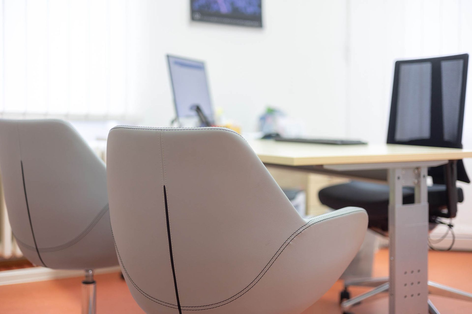 In einem Büro stehen zwei Stühle vor einem Schreibtisch.