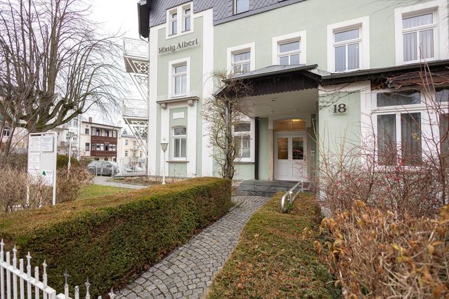 Ein großes grünes Gebäude mit einem weißen Zaun davor.