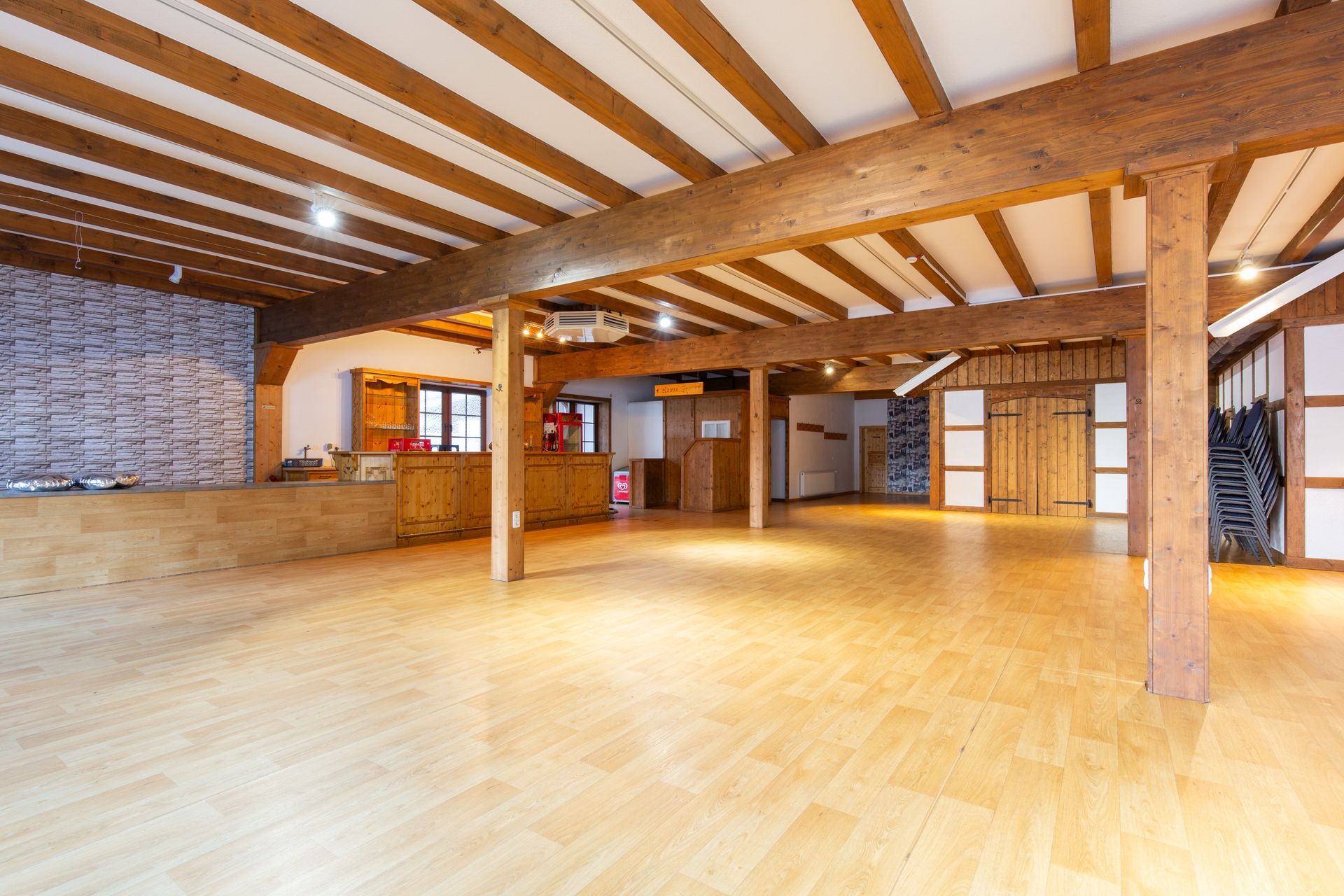 Ein großer leerer Raum mit Holzbalken und Holzboden