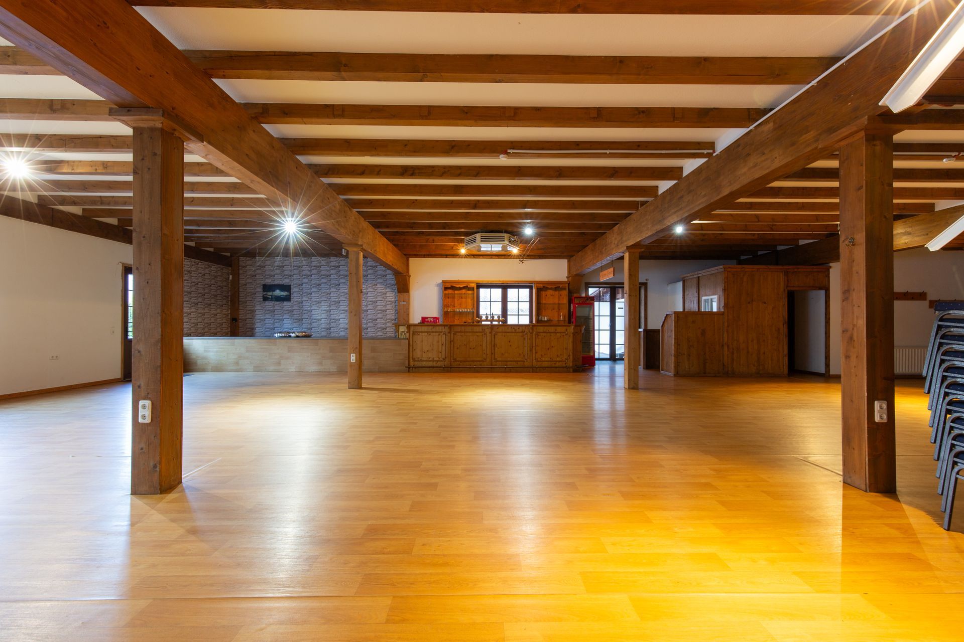 Ein großer leerer Raum mit Holzbalken und Holzboden.