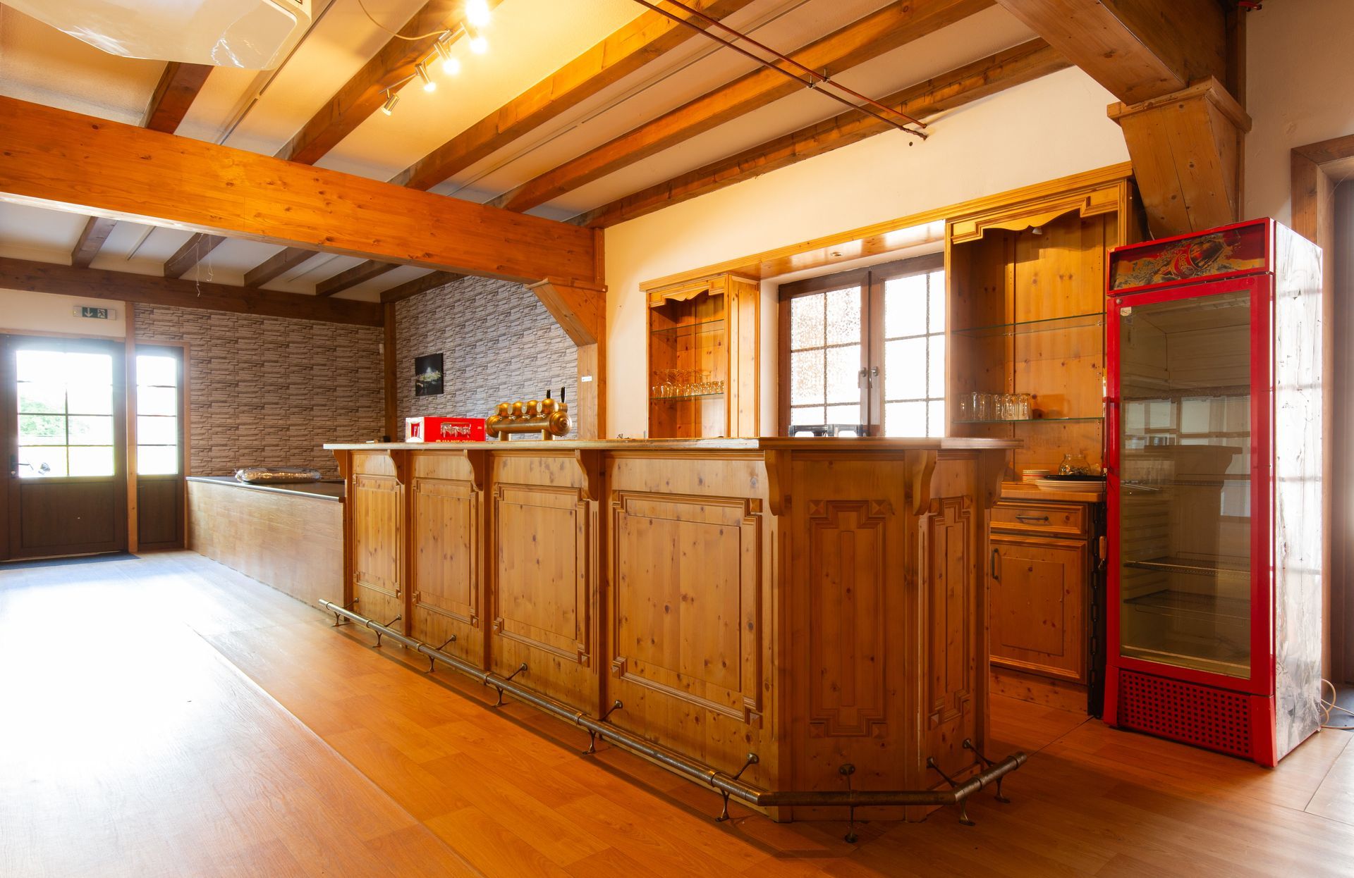 Ein großer Raum mit einer Holzbar und einem Coca-Cola-Kühlschrank