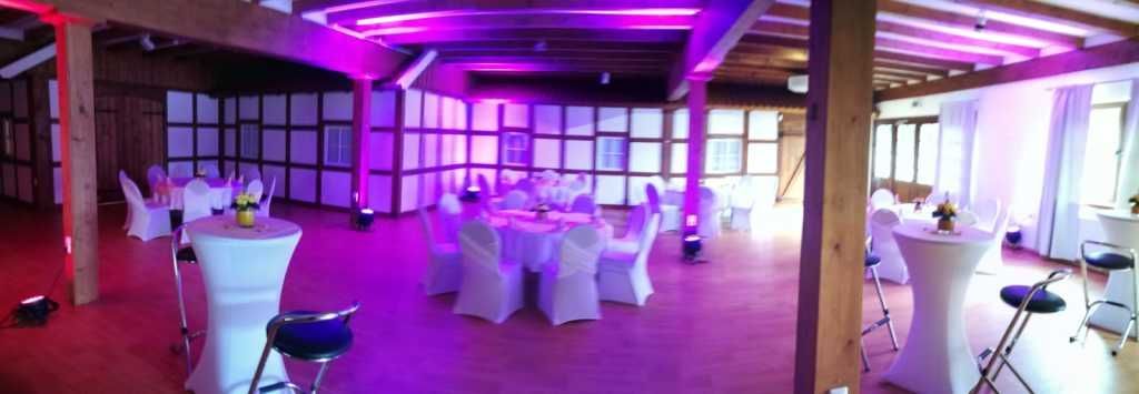 Ein großer Raum mit Tischen und Stühlen, aufgestellt für einen Hochzeitsempfang.