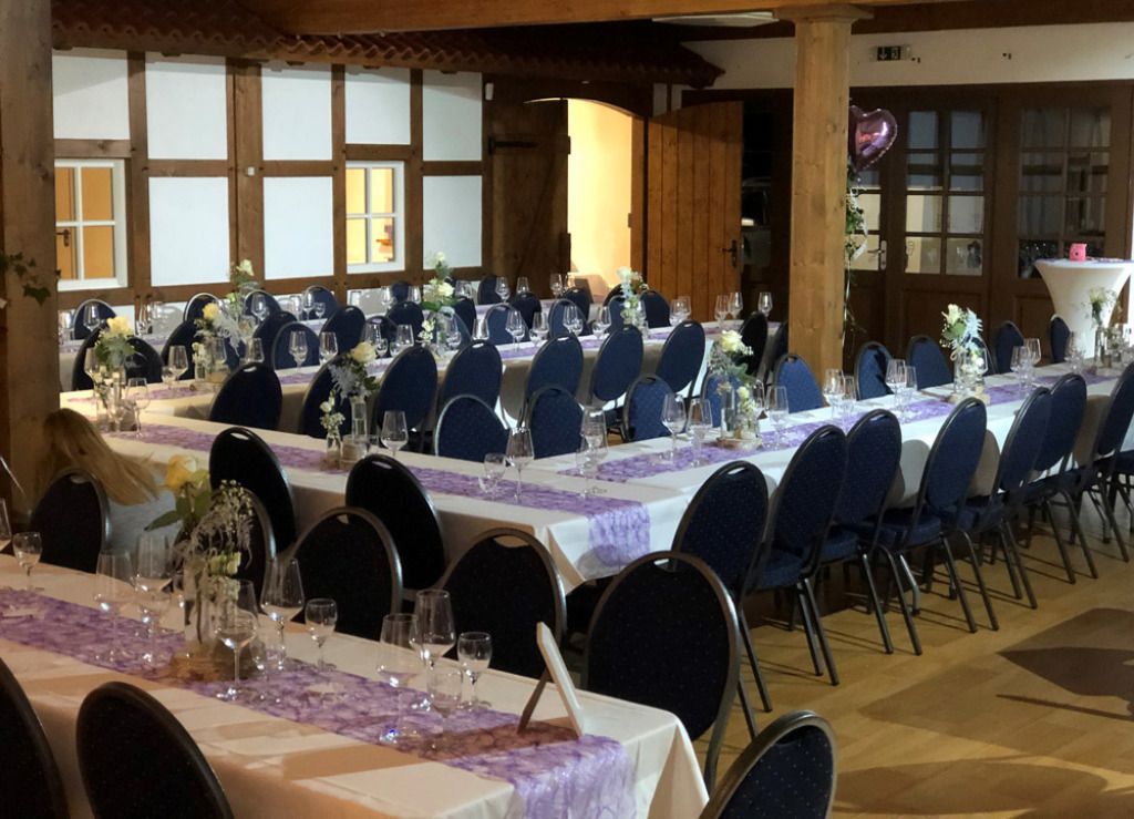 Ein großer Raum mit Tischen und Stühlen, aufgestellt für einen Hochzeitsempfang.