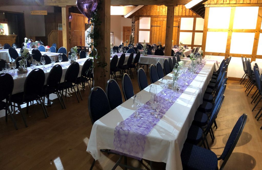 Ein großer Raum mit Tischen und Stühlen, aufgestellt für einen Hochzeitsempfang.