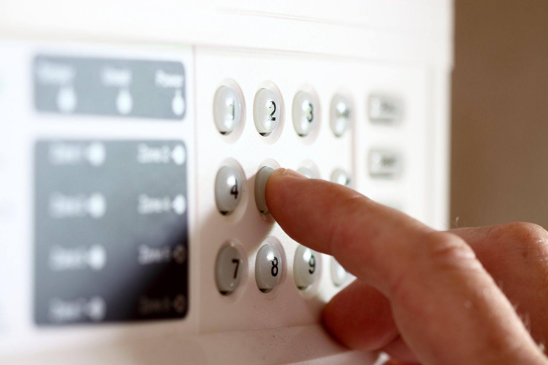 Appuyer du doigt sur un clavier de sécurité domestique avec des touches blanches rétroéclairées et un petit écran.