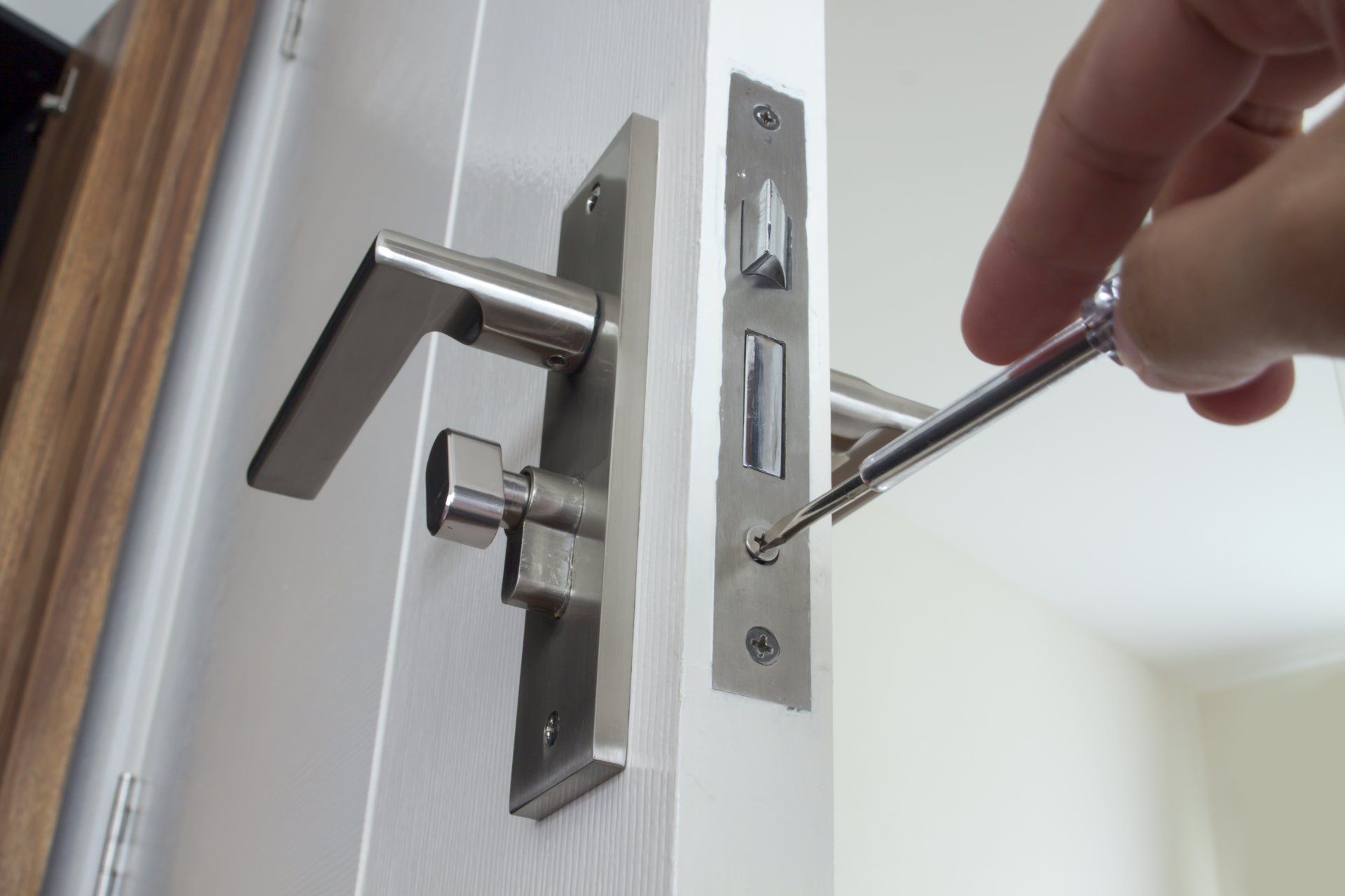 Serrage manuel d'un loquet de porte à l'aide d'un tournevis sur un cadre de porte blanc