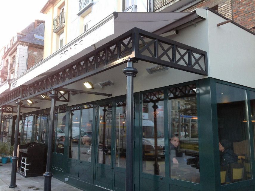 Façade de magasin avec vitrines et auvent en métal noir sur une rue de la ville