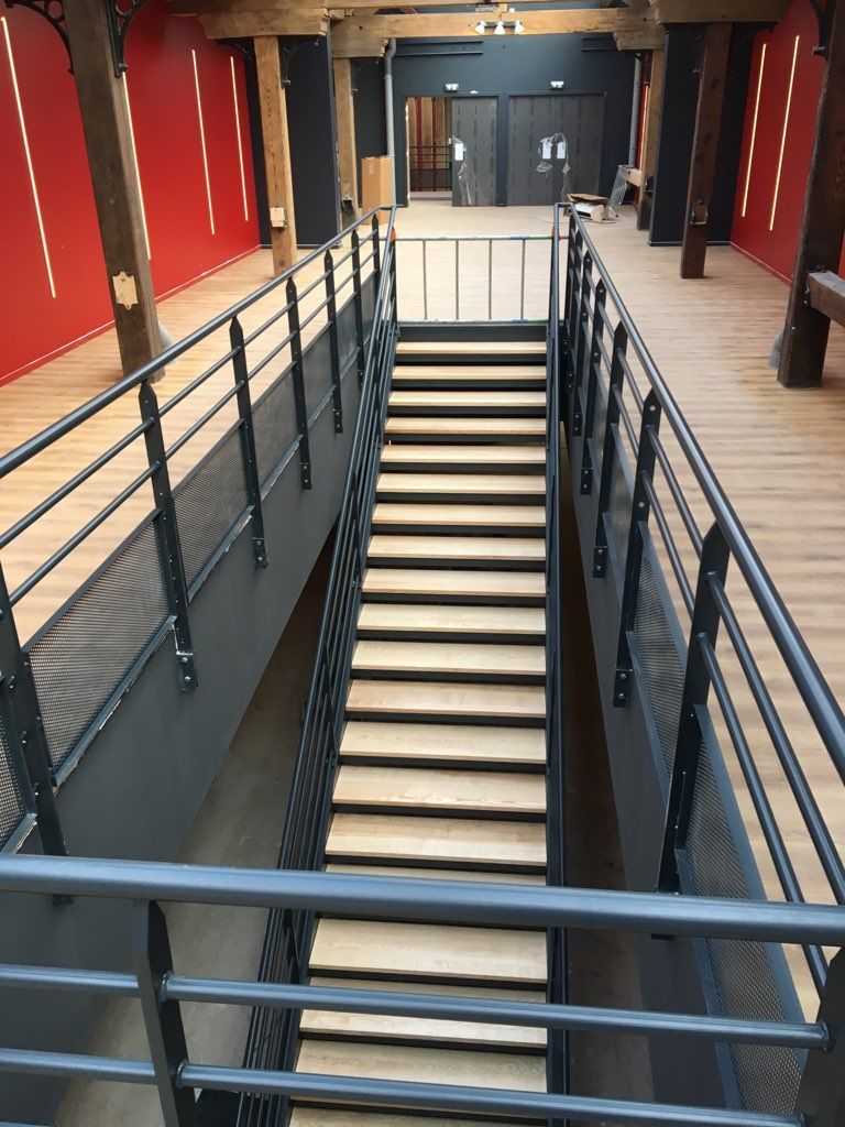 Escalier à rampes noires menant à une porte dans un hall intérieur aux murs rouges