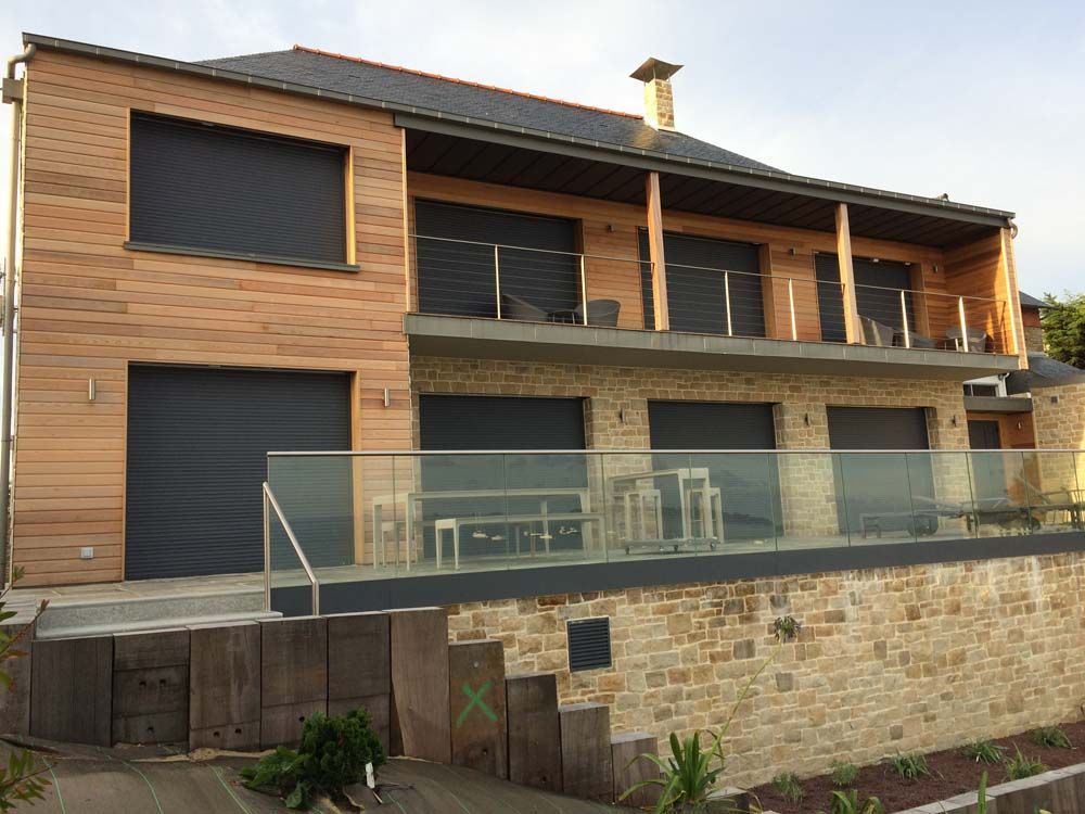 Maison moderne de deux étages avec bardage en bois, grandes fenêtres et terrasse en pierre en construction
