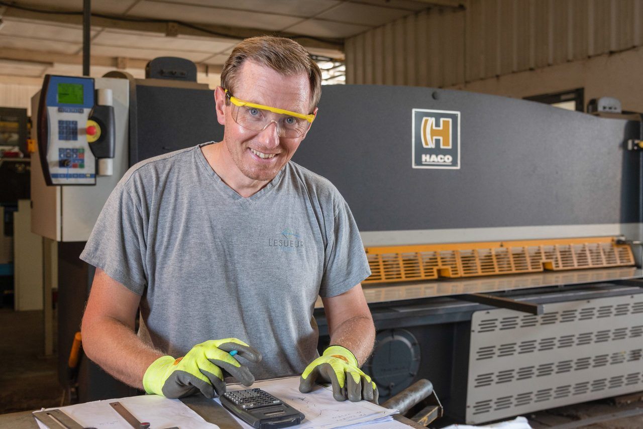 Ouvrier portant des lunettes et des gants de sécurité manipulant une machine dans un atelier